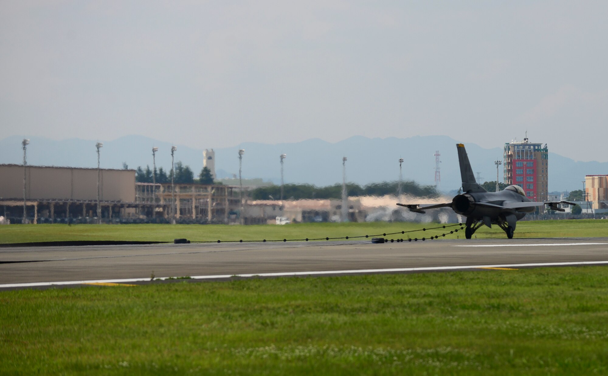 An F-16 Fighting Falcon from Misawa Air Base, Japan, slows down on the runway at Yokota Air Base, Japan, June 24, 2015. As the reel of the aircraft arresting system spins it activates a hydraulic pump which compresses a brake pad to safely slow the aircraft. The aircraft can go from a speed of 180 knots to a complete hault in approximately 10 seconds. (U.S. Air Force photo by Senior Airman David Owsianka/Released)