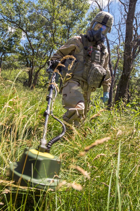 Army Staff Sgt. Michael Aldrich scans the ground with a metal detector in search of possible explosives during chemical, biological, radiological, nuclear, and explosive scenario training as part of Patriot Warrior at Fort McCoy, Wis., June 16, 2015. Aldrich is assigned to the 46th Chemical Company.