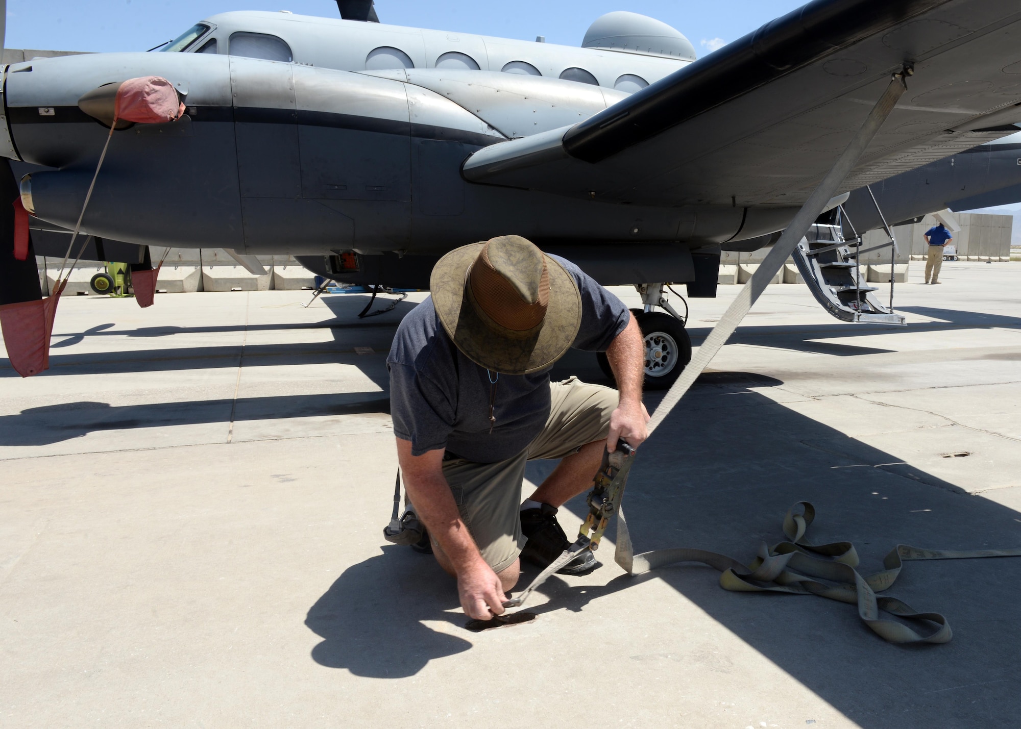 Shawn Hall, 455th Expeditionary Aircraft Maintenance Squadron aircraft mechanic, straps down an MC-12W aircraft due to high winds June 26, 2015, at Bagram Airfield, Afghanistan. Hall is part of the Project Liberty team that is deployed here in support of NATO’s Resolute Support mission. (U.S. Air Force photo by Senior Airman Cierra Presentado/Released)