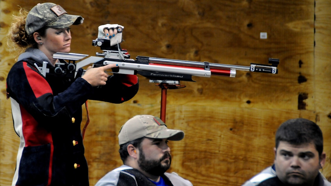 Medically retired Marine Sgt. Janae Piper, looks over her air rifle as her competitors, Air Force Staff Sgt. Seth Pena and Air Force Master Sgt. Daniel Waugh wait for the air rifle competition to begin at the 2015 DoD Warrior Games at Marine Corps Base Quantico, Virginia, June 26, 2015. Piper earned the gold medal, Waugh earned the silver medal and Pena earned the bronze medal for the event.