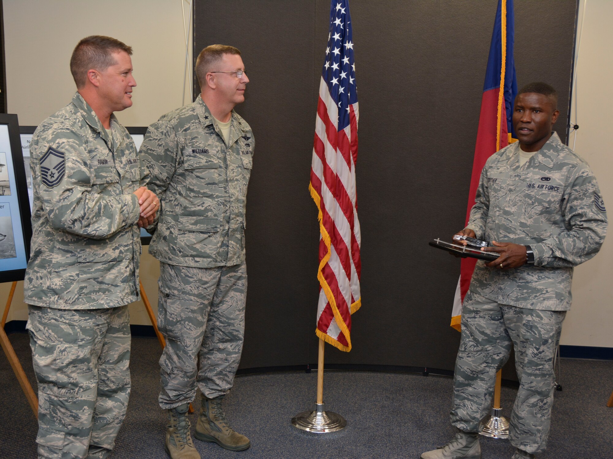 U.S. Air Force Tech. Sgt. Francis Strother (right), 145th Force Support Squadron, is presented a Regional Golden Eagle Award for top overall accessions in 2014 from Brig. Gen. Roger E. Williams, Jr. (center), Assistant Adjutant General for Air, North Carolina Air National Guard, as Senior Master Sgt. Robert Ramsay, (left) Recruiting and Retention Superintendent, looks on during a ceremony held at the North Carolina Air National Guard base, Charlotte Douglas International Airport, N.C., June 6, 2015. The 145th FSS recruiting and retention office won the team Regional Golden Eagle Award as well as seven individual awards. (U.S. Air National Guard photo by Senior Airman Laura Montgomery, 145th Public Affairs/Released)