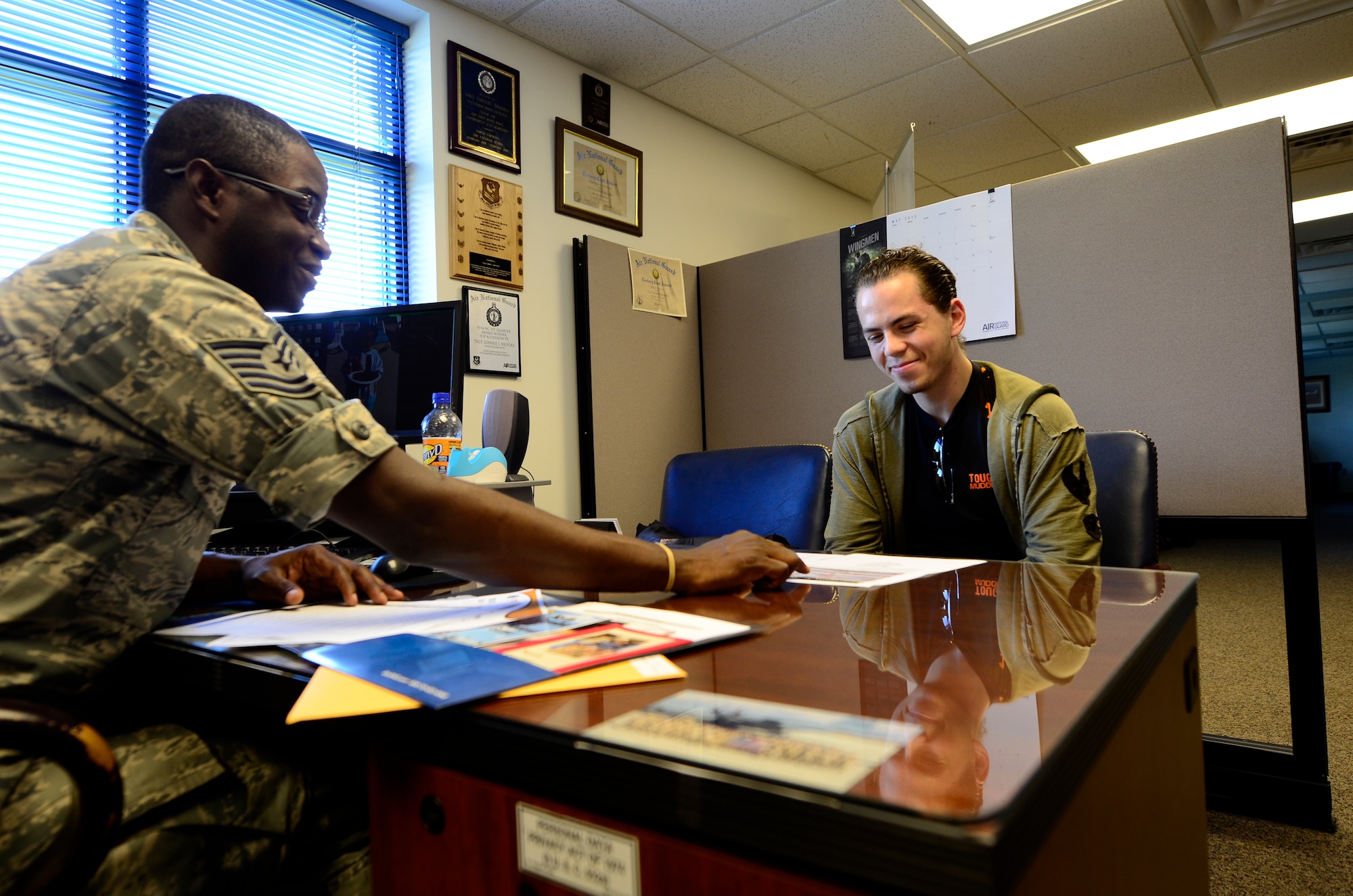 U.S. Air Force Tech. Sgt. Lonnie Brooks, production recruiter for the 145th Force Support Squadron, explains education benefits to Cristofer Grit (right) June 17, 2015, at North Carolina Air National Guard base, Charlotte Douglas International Airport, N.C., Grit, who is originally from Moldova, moved to the U.S. to pursue his passion in culinary arts and is now interested in joining the N.C. Air National Guard. (U.S. Air National Guard photo by Staff Sgt. Julianne M. Showalter, 145th Public Affairs/Released)