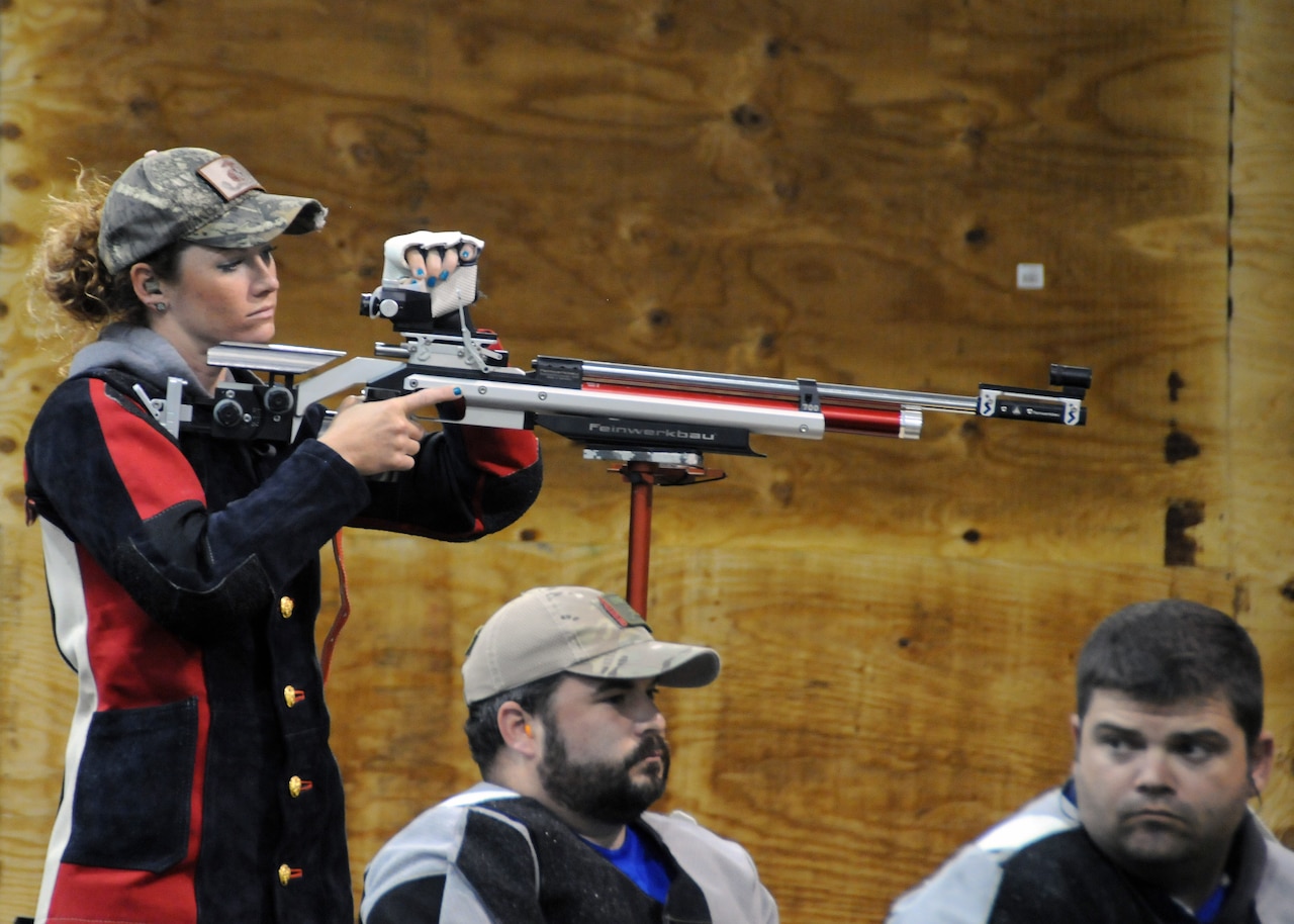 Medically retired Marine Corps Sgt. Janae Piper looks over her air rifle as fellow competitors Air Force Staff Sgt. Seth Pena and Air Force Master Sgt. Daniel Waugh, wait for the air rifle competition to begin at the 2015 DoD Warrior Games at Marine Corps Base Quantico, Va., June 26, 2015. Piper earned the gold medal, Waugh earned the silver medal and Pena earned the bronze medal for the event. DoD photo by Shannon Collins