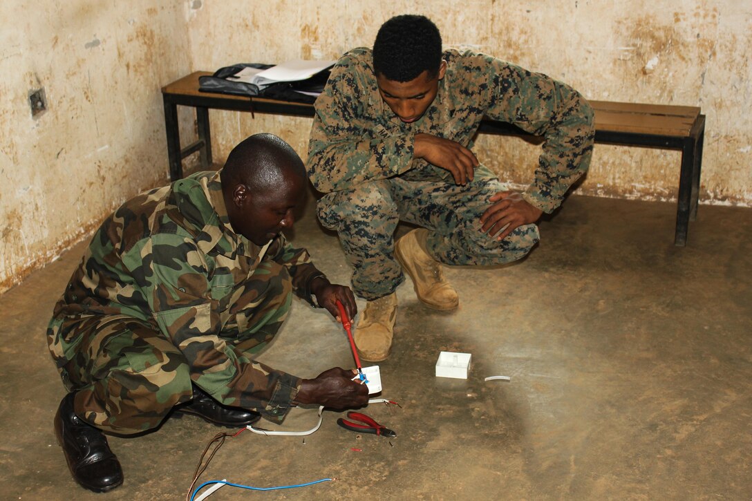 U.S. Marine Cpl. Eric Hairston, an electrical equipment mechanic, observes a Ugandan soldier complete a wiring project at Camp Singo, Uganda, March 2,
2015. More than 20 U.S. Marines and Sailors with Special-Purpose Marine Air-Ground Task Force Crisis Response-Africa trained with Ugandan Soldiers during a three-month mission, which allowed the UPDF to increase mission-specific capabilities in logistics and engineering for upcoming deployments throughout Africa. (Courtesy Photo/Released)