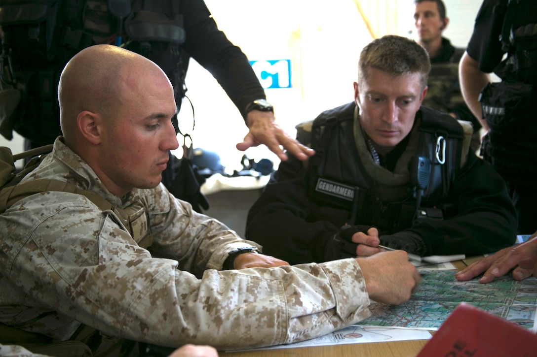 U.S. Marine 1st Lt. Scott Vicino, left, a platoon commander with Special-Purpose Marine Air-Ground Task Force Crisis Response-Africa, and French Capt. Guillaume Deckmyn, a company commander with France’s Gendarmerie, prepare for a hostage recovery exercise at the National Gendarmerie Training Center in St. Astier, France, June 19, 2015. The two groups coordinated the rescue of three hostages simultaneously amidst the chaos of a simulated riot. (U.S. Marine Corps photo by 1st Lt. Danielle Dixon/Released)