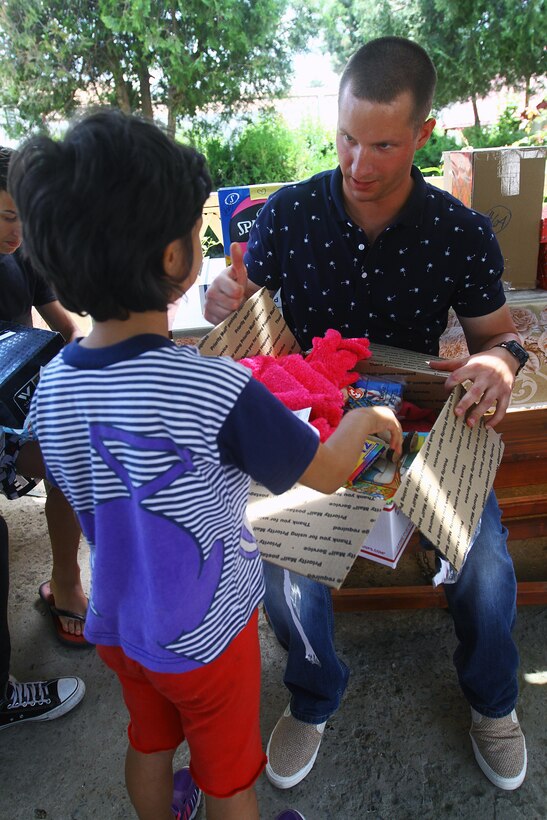 U.S. Marine Lance Cpl. Steven J. White helps a child open a gift box given by generous Americans provided in a partnership through an organization called United Hands Romania, a nonprofit that works alongside other nonprofits in the United States. The child is part of a group home for neglected children that falls under the Child Protective Agency of Romania. White is a chemical, biological, radiological and nuclear defense specialist with Black Sea Rotational Force.