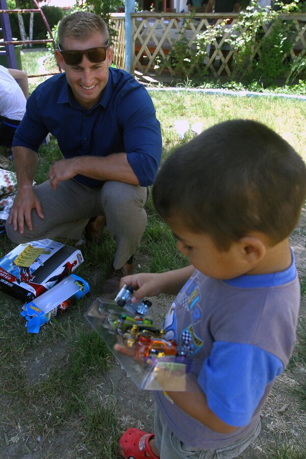 U.S. Marine Capt. Matthew J. Gordon helps a child unwrap a toy given by generous Americans provided in a partnership through an organization called United Hands Romania, a nonprofit that works alongside other nonprofits in the United States. The child is part of a group home for neglected children that falls under the Child Protective Agency of Romania. Gordon is a signals intelligence officer with Black Sea Rotational Force.