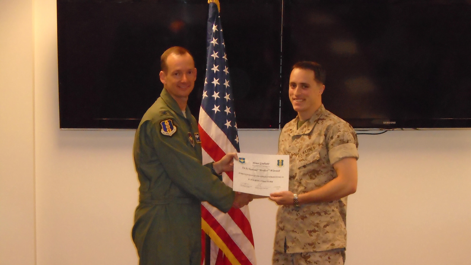 Col. Christopher Niemi, 33rd Operations Group commander, presents U.S. Marine Corps 1st Lt. Samuel Winsted, F-35B Lightning II intelligence officer, a graduation certificate after completing the F-35 Intelligence Formal Training Unit course, June 24, 2015, on Eglin Air Force Base, Florida. Winsted will serve in a critical role assisting the Marine Corps’ F-35 program at Marine Corps Air Station Yuma, Arizona, as it becomes the first operational F-35B base. The Marine Corps will declare IOC with the F-35B, short take-off and vertical landing variant, this summer. (U.S. Air Force courtesy photo)