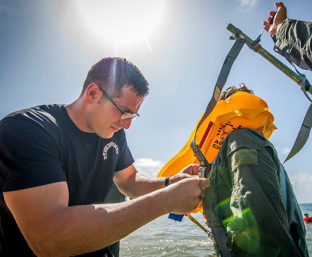 Staff Sgt. Austin Aluis, 315th Operations Support Squadron SERE instructor, assists an Airman with her life preserver moments before the body drag portion of the water survival course June 27, 2015, at Naval Air Station Key West, Fla. The SERE program was established by the U.S. Air Force after the Korean War, and was extended to other branches during the Vietnam War. In addition to teaching military service members with the techniques for survival, they also teach military code of conduct.  (U.S. Air Force photo by Senior Airman Tom Brading)