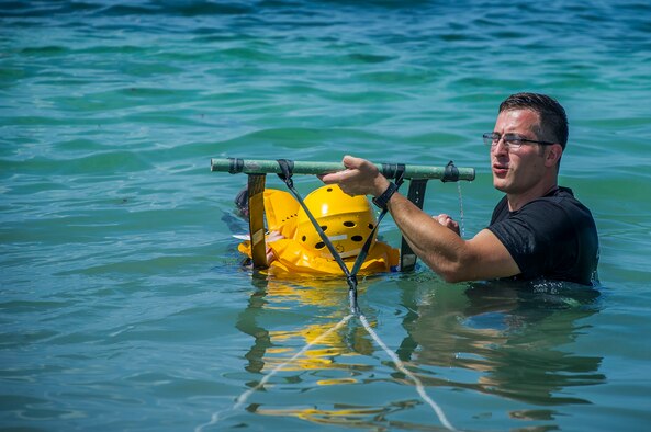 Staff Sgt. Austin Aluis, 315th Operations Support Squadron SERE instructor, assists an Airman with her life preserver moments before the body drag portion of the water survival course June 27, 2015, at Naval Air Station Key West, Fla. The SERE program was established by the U.S. Air Force after the Korean War, and was extended to other branches during the Vietnam War. In addition to teaching military service members with the techniques for survival, they also teach military code of conduct.  (U.S. Air Force photo by Senior Airman Tom Brading)