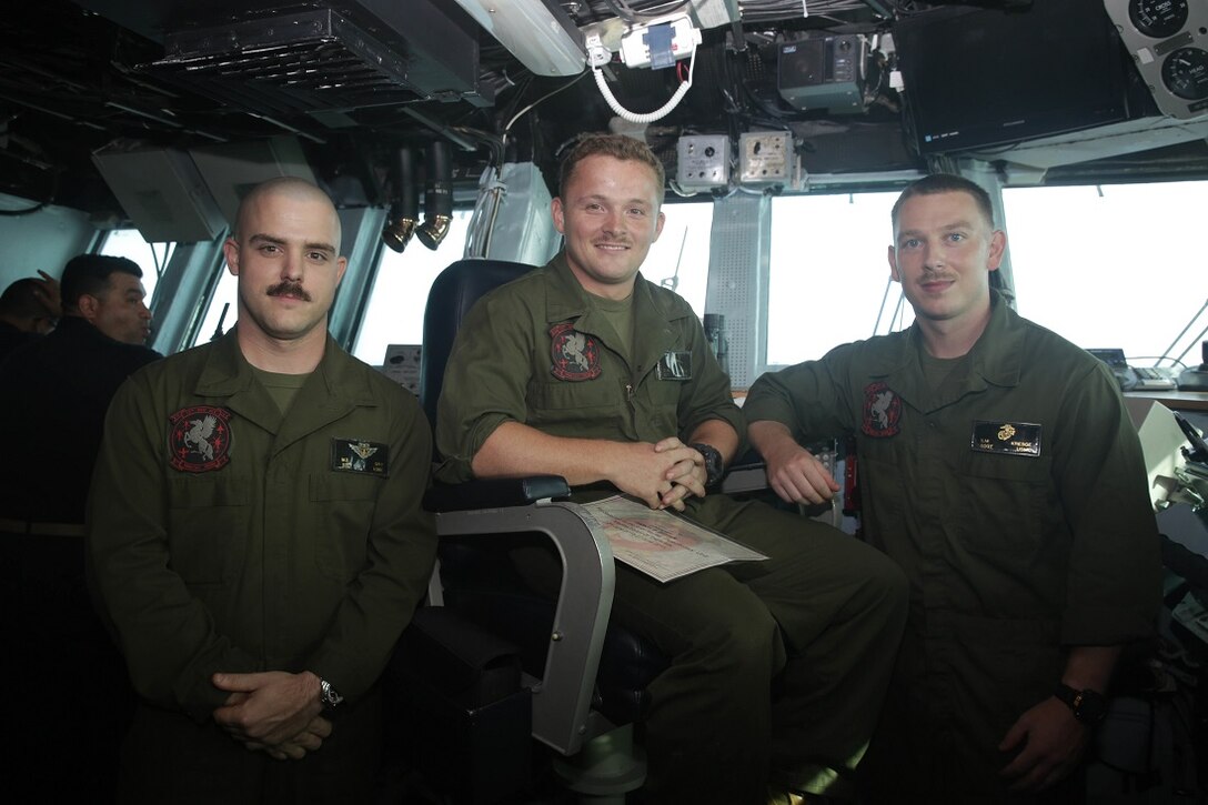 ARABIAN SEA (June 26, 2015) U.S. Marine Cpl. Damon Dryden, middle, sits in the captain’s chair of the USS Essex (LHD 2) next to Staff Sgt. Matthew Spry, left, and Staff Sgt. Shane Kresge after being awarded the 15th Marine Expeditionary Unit “Marine of the Week.” Dryden is an AV-8B Harrier airframes mechanic with Marine Medium Tiltrotor Squadron 161 (Reinforced), 15th MEU and from Jeffersonville, Indiana. Spry and Kresge are both with VMM-161 (Rein.), 15th MEU. Dryden’s maintenance work ethic, leadership and knowledge are apparent throughout the shop and contagious among the Marines he mentors and works with. The 15th MEU is embarked on the Essex Amphibious Ready Group and deployed to maintain regional security in the U.S. 5th Fleet area of operations. (U.S. Marine Corps photo by Cpl. Anna Albrecht/Released)
