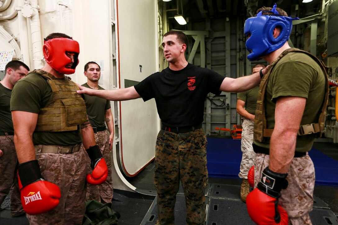 ARABIAN SEA (June 24, 2015) U.S. Marine Cpl. Ryan Jackson, middle, teaches his students how to set up a sparring match during a Martial Arts Instructor Course aboard the USS Anchorage (LPD 23).  Jackson is a rifleman and a martial arts instructor trainer with Battalion Landing Team 3rd Battalion, 1st Marine Regiment, 15th Marine Expeditionary Unit. The students are going through the rigorous course in order to become MCMAP instructors for their respective units. Anchorage is part of the Essex Amphibious Ready Group, and, with the embarked 15th MEU, is deployed in support of maritime security operations and theater security cooperation efforts in the U.S. 5th Fleet area of operations. (U.S. Marine Corps photo by Sgt. Jamean Berry/ Released)