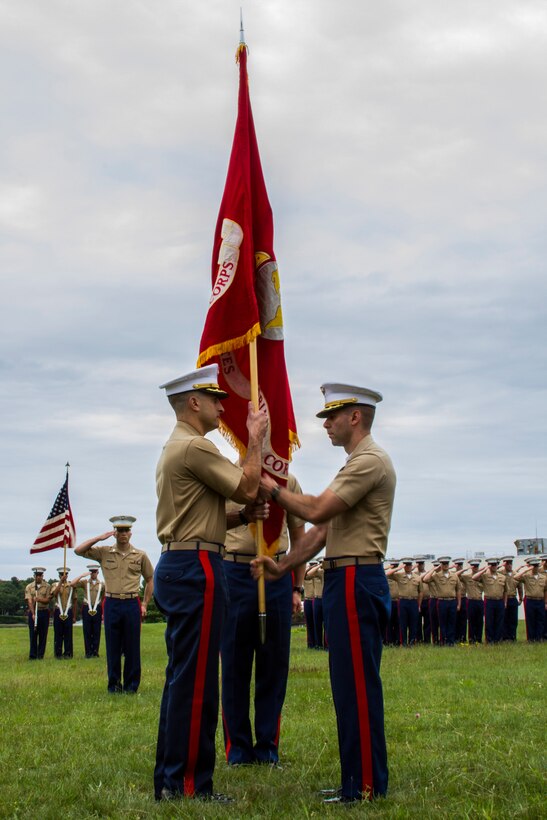 Major Andrew Gourgoumis, outgoing commanding officer of Recruiting Station Portsmouth, New Hampshire, hands the Marine Corps colors to Maj. Stephen Boada during the change of command ceremony, June 26. Boada is coming from his position as inspector-instructor of Battery P., 5th Battalion, 14th Marines in Spokane, Washington, and Gourgoumis is heading to the Command and Staff College aboard Marine Corps Base Quantico, Virginia.