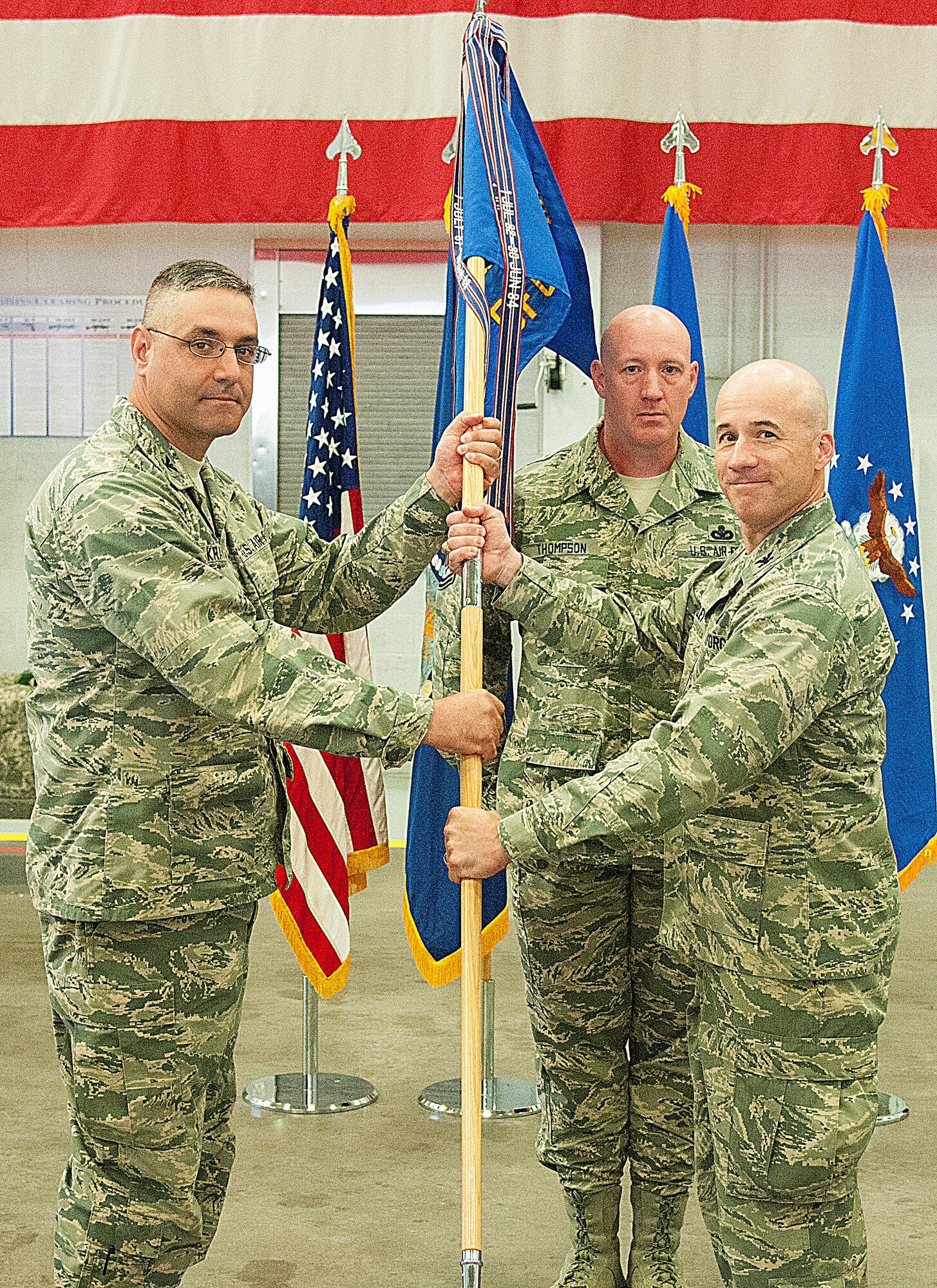 Col. Stephen Kravitsky, 90th Missile Wing commander, passes the guidon to Col. Christopher Corley, 90th Security Forces Group commander, during the 90th SFG change of command ceremony June 29, 2015, as Chief Master Sgt. Stephen Thompson, 90th SFG chief enlisted manager, stands in the background in the Peacekeeper High Bay on F.E. Warren Air Force Base, Wyo. The ceremony signified the transition of command from Col. Craig Allton to Corley. (U.S. Air Force photo by Senior Airman Jason Wiese)