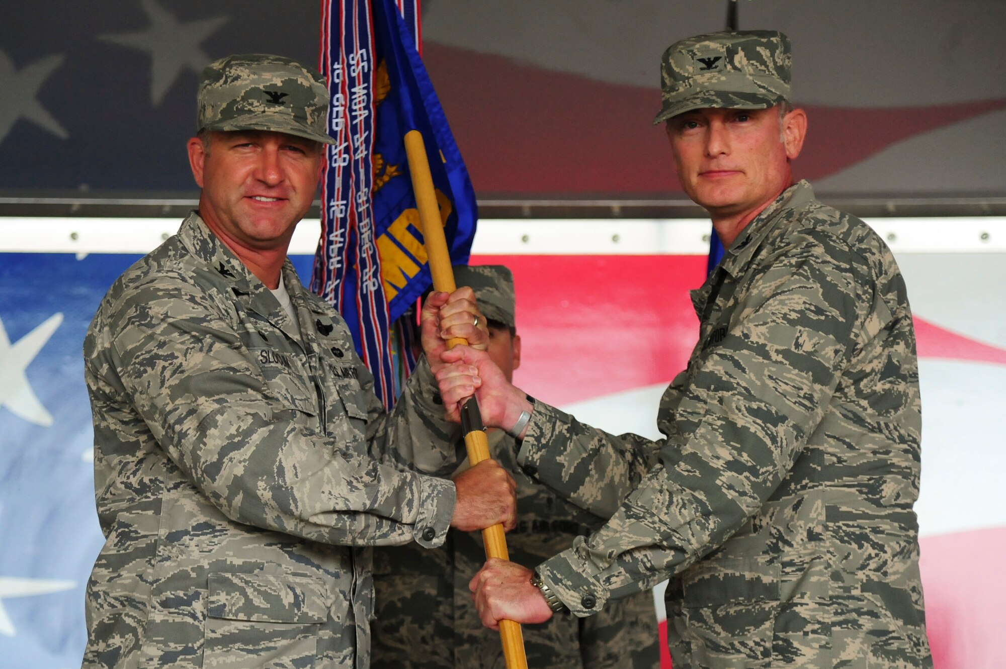 Col. Mark Slocum (left), 4th Fighter Wing commander, passes the guidon to Col. Paul Conner, incoming 4th Medical Group commander, during a change of command ceremony, June 25, 2015, at Seymour Johnson Air Force Base, North Carolina. Conner is a board-certified healthcare administrator and previously served as the chief financial officer and director of business operations for the San Antonio Military Health System. (U.S. Air Force photo/Senior Airman Brittain Crolley)
