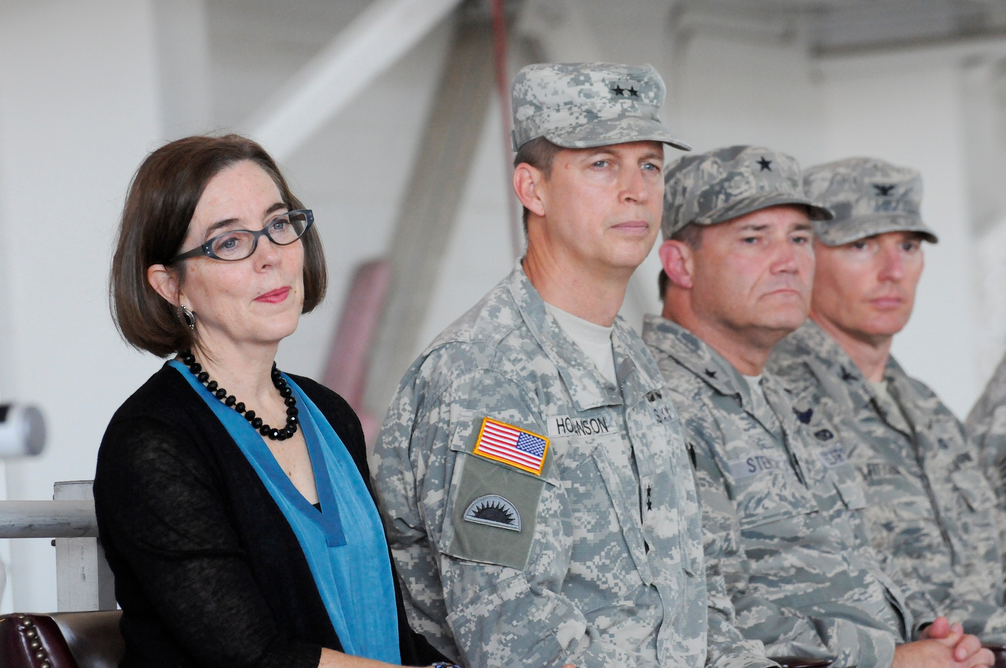 Members of the official party, left to right, Oregon Governor Kate Brown, Oregon Adjutant General Daniel Hokanson, Oregon Air National Guard Commander Michael Stencel and 142nd Fighter Wing Commander Col. Paul Fitzgerald listen to music performed by the 234th Army National Guard Band during the 142nd Fighter Wing mobilization ceremony, June 26, 2015, Portland Air National Guard Base, Ore. (U.S. Air National Guard photo by Tech. Sgt. John Hughel, 142nd Fighter Wing Public Affairs/Released)