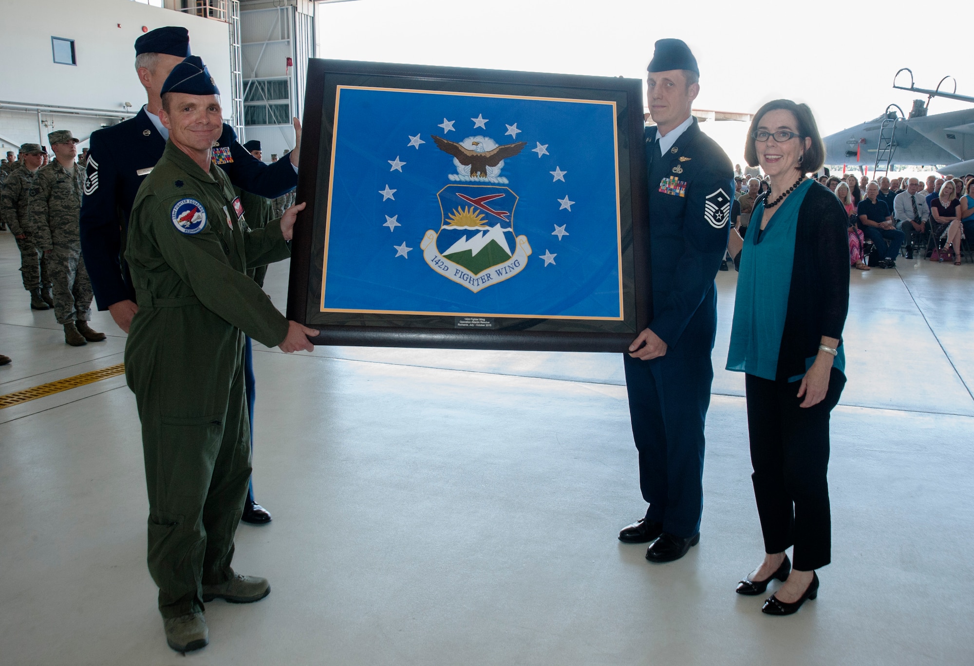 Oregon Air National Guard Lt. Col. Sean Sullivan, 123rd Fighter Squadron commander, 142nd Fighter Wing, left, presents the unit flag of the 142nd Fighter Wing to Oregon Governor Kate Brown during the unit’s mobilization ceremony, June 26, 2015, Portland Air National Guard Base, Ore. (U.S. Air National Guard photo by Tech. Sgt. John Hughel, 142nd Fighter Wing Public Affairs/Released)