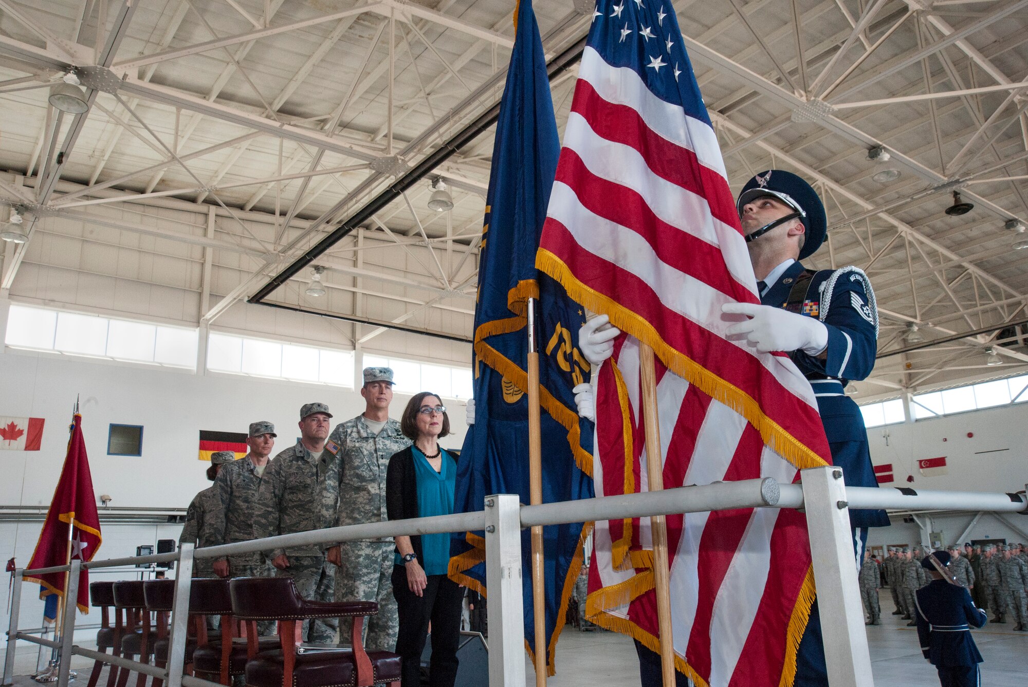 A member of the 142nd Fighter Wing Base Honor Guard post the American Flag while Oregon Governor Kate Brown and other members of the official party pause during the mobilization ceremony for the 142nd Fighter Wing, June 26, 2015, Portland Air National Guard Base, Ore.  (U.S. Air National Guard photo by Tech. Sgt. John Hughel, 142nd Fighter Wing Public Affairs/Released)