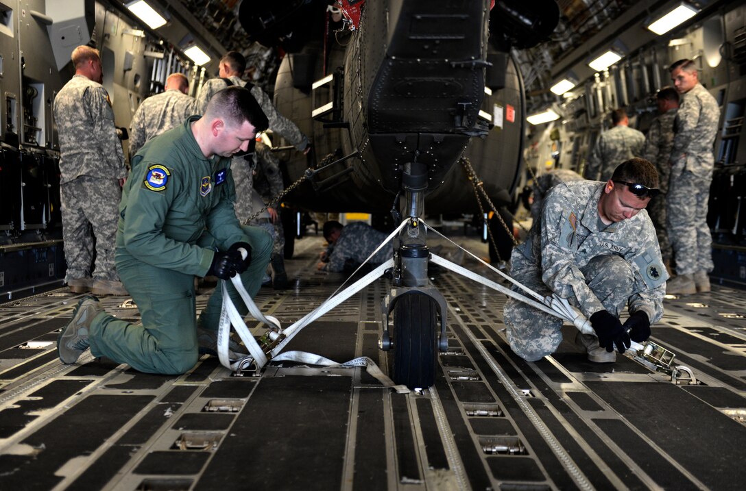 A C-17 loadmaster assigned to Joint Base McGuire-Dix-Lakehurst, New Jersey and a UH-60 Blackhawk repairman work together to tie down a UH-60 to a C-17 June 25, 2015 at Soto Cano Air Base, Honduras. The helicopter traveled back to Fort Bragg, South Carolina to receive a complete maintenance inspection. (U.S. Air Force photo by Staff Sgt. Jessica Condit)