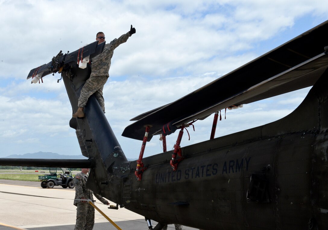 Sgt. Christopher Frost, a 1-228th Aviation Regiment Blackhawk repairman, reassures the crew loading a UH-60 that everything is clear by issuing a “thumbs up” June 25, 2015, at Soto Cano Air Base, Honduras. The crew loaded the 13,000 pound Blackhawk onto a C-17 bound for Fort Bragg, South Carolina to have it inventoried and refurbished. (U.S. Air Force photo by Staff Sgt. Jessica Condit)