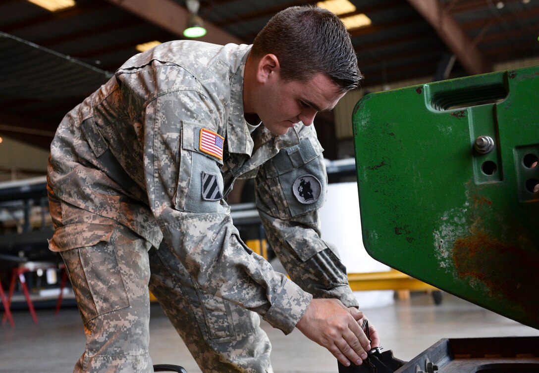Spc. Matthew Greathouse, a 1-228th Aviation Regiment UH-60 crew chief, hooks a Blackhawk to a tractor June 25, 2015, at Soto Cano Air Base, Honduras. The helicopter was loaded onto a C-17 from Joint Base McGuire-Dix-Lakehurst, New Jersey in order to be refurbished. (U.S. Air Force photo by Staff Sgt. Jessica Condit)