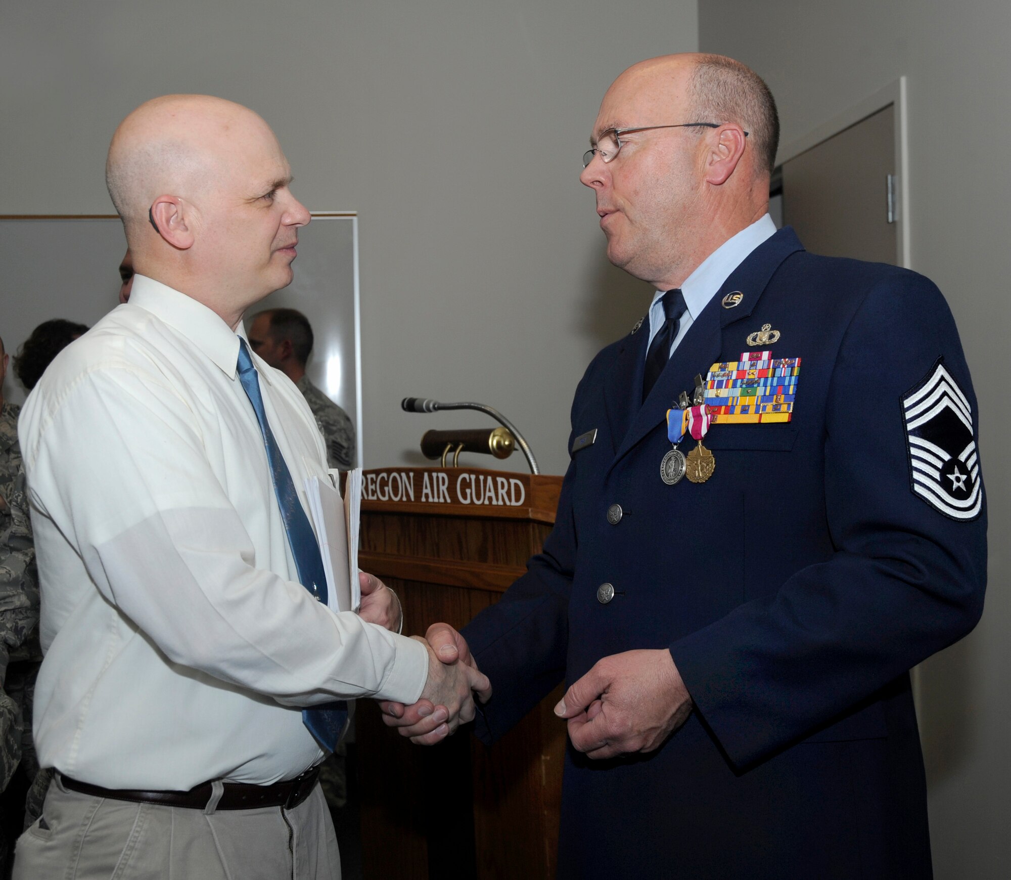 Retired Air Force Lt. Col. Terry Popravak, 142nd Fighter Wing volunteer base historian, left, congratulates retired Chief Master Sgt. Patrick Tracy, right, at the conclusion of his formal retirement ceremony, May 2, 2015, Portland Air National Guard Base, Ore. Tracy was assigned to the 142nd Fighter Wing Operations Group, serving as the senior enlisted leader and also was the Team Chief for the Air National Guard’s F-15 Eagle Weapons System Council, Aircrew Flight Equipment. (U.S. Air National Guard by Tech. Sgt. John Hughel, 142nd Fighter Wing Public Affairs Department)