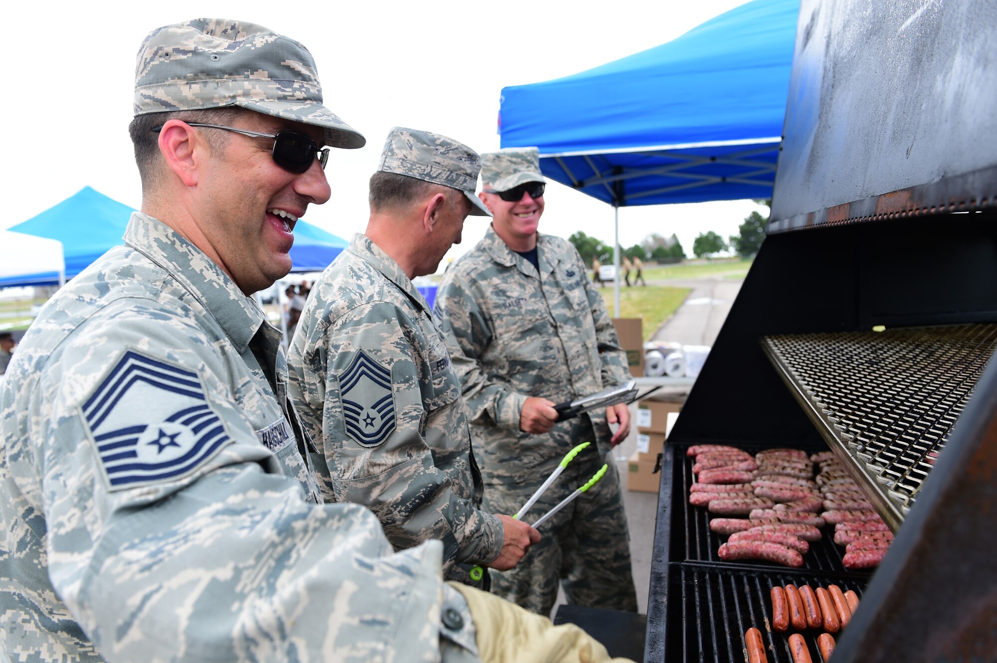 Members of the Buckley Chief’s Group grill hot dogs and sausages for Junior Enlisted Appreciation Day June 26, 2015, at the all-purpose field on Buckley Air Force Base, Colo. Junior Enlisted Appreciation Day is held annually to recognize the efforts of E-4s and below on Buckley AFB. (U. S. Air Force photo by Airman 1st Class Luke W. Nowakowski/Released)