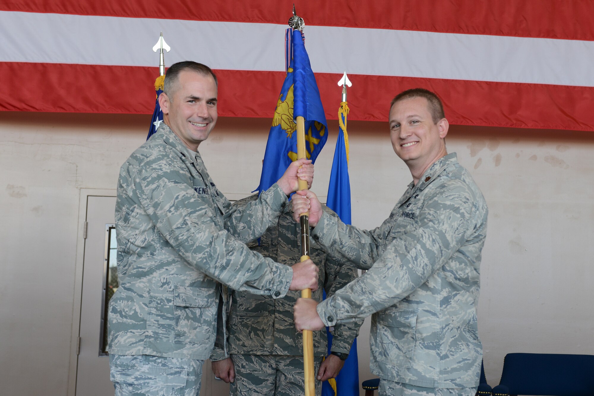 U.S. Air Force Lt. Col. Bart Kenerson, the 354th Maintenance Group commander, passes the 354th Maintenance Squadron guidon to Maj. Timothy Stokes, the new 354th MXS commander, June 29, 2015, at Eielson Air Force Base, Alaska. Maj. Phillip Broyles, the outgoing squadron commander, will move on to Hurlburt Field, Fla. (U.S. Air Force photo by Senior Airman Ashley Nicole Taylor/Released)