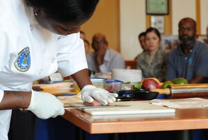 Staff Sgt. Tasha Goodrich, Air Force Enlisted Aide demonstrates how to remove skin from a salmon filet during the Healthy Cooking Made Easy demonstration at Liberty Park Welcome Center on Joint Base Andrews, Md., June 25, 2015. (U.S. Air Force photo/ Staff Sgt. Nichelle Anderson)