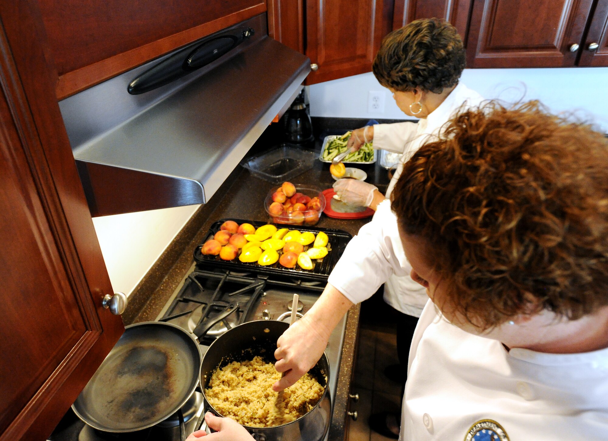 Chief Master Sgt. Laura Kelly and Bessie Powers  prepare food for the Healthy Cooking Made Easy demonstration at Liberty Park Welcome Center on Joint Base Andrews, Md., June 25, 2015. Kelly is an Air Force Enlisted Aide and Powers volunteered to help with the event. (U.S. Air Force photo/ Staff Sgt. Nichelle Anderson)