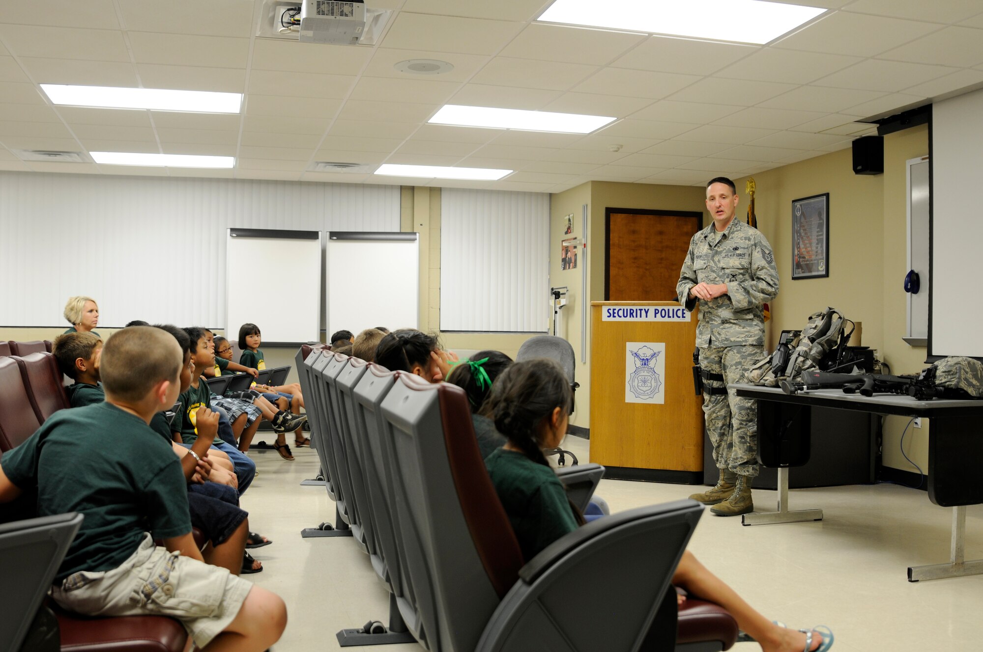 Tech. Sgt. Frank Koeth, 188th Security Forces specialist, speaks to Choctaw Nation students during a base tour at Ebbing Air National Guard Base, Ark., June 25, 2015. Koeth explained the importance of various items that security forces members carry at home station and when deployed and how they are utilized for their missions. During the tour kids viewed static displays of former 188th aircraft and met Airmen from three key 188th squadrons to include security forces, intelligence and operations. (U.S. Air National Guard photo by Staff Sgt. Hannah Dickerson/Released)