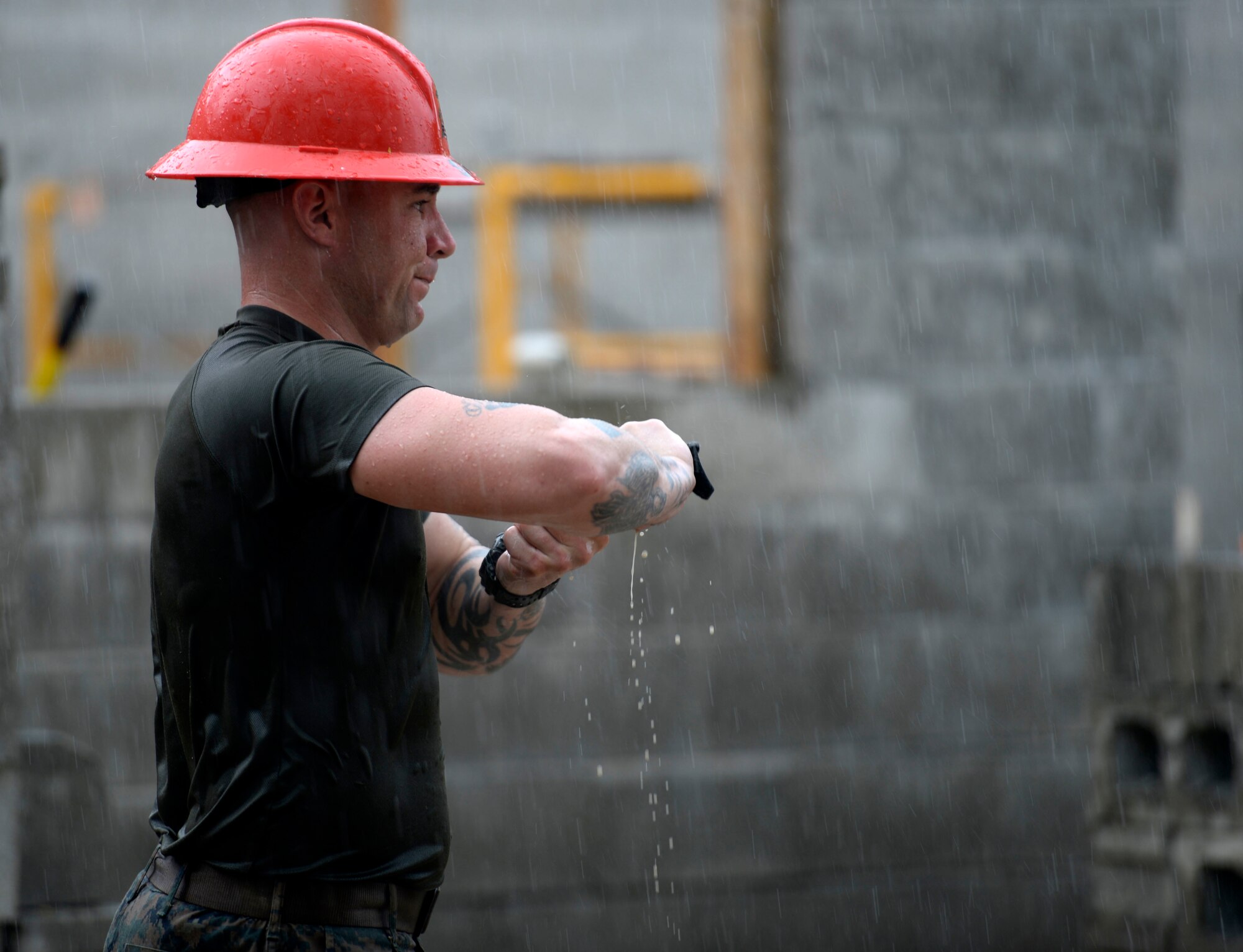 U.S. Marine Staff Sgt. Andrew Smith, a combat engineer with a 271st Marine Wing Support Squadron, 2nd Marine Air Wing, wrings out his gloves during a downpour at the Gabriela Mistral school construction site in Ocotes Alto, Honduras, June 24, 2015. The school project is one part of the NEW HORIZONS Honduras 2015, an annual humanitarian and training exercise put on by U.S. Southern Command. NEW HORIZONS was launched in the 1980s and is an annual joint humanitarian assistance exercise that U.S. Southern Command conducts with a partner nation in Central America, South America or the Caribbean. The exercise improves joint training readiness of U.S. and partner nation civil engineers, medical professionals and support personnel through humanitarian assistance activities. (U.S. Air Force photo by Capt. David J. Murphy/Released)
