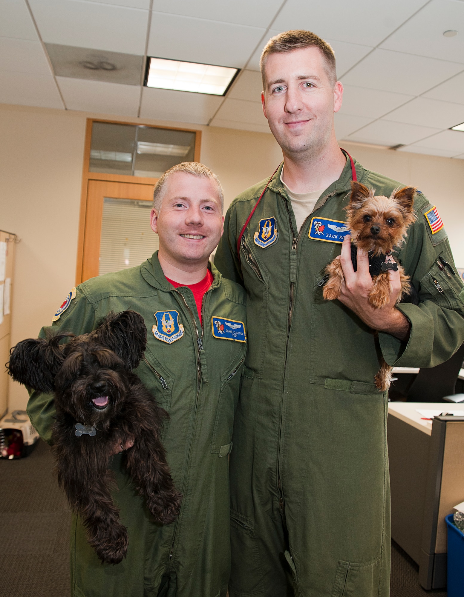 Tech Sgt. Shane Clayton and Capt. Zack Kiel, 732d Airlift Squadron pose with their dogs Lilly, a miniature schnauzer, and Niko, a Yorkshire terrier, during the national Take Your Dog to Work day (U.S. Air Force photo/Christian DeLuca)
