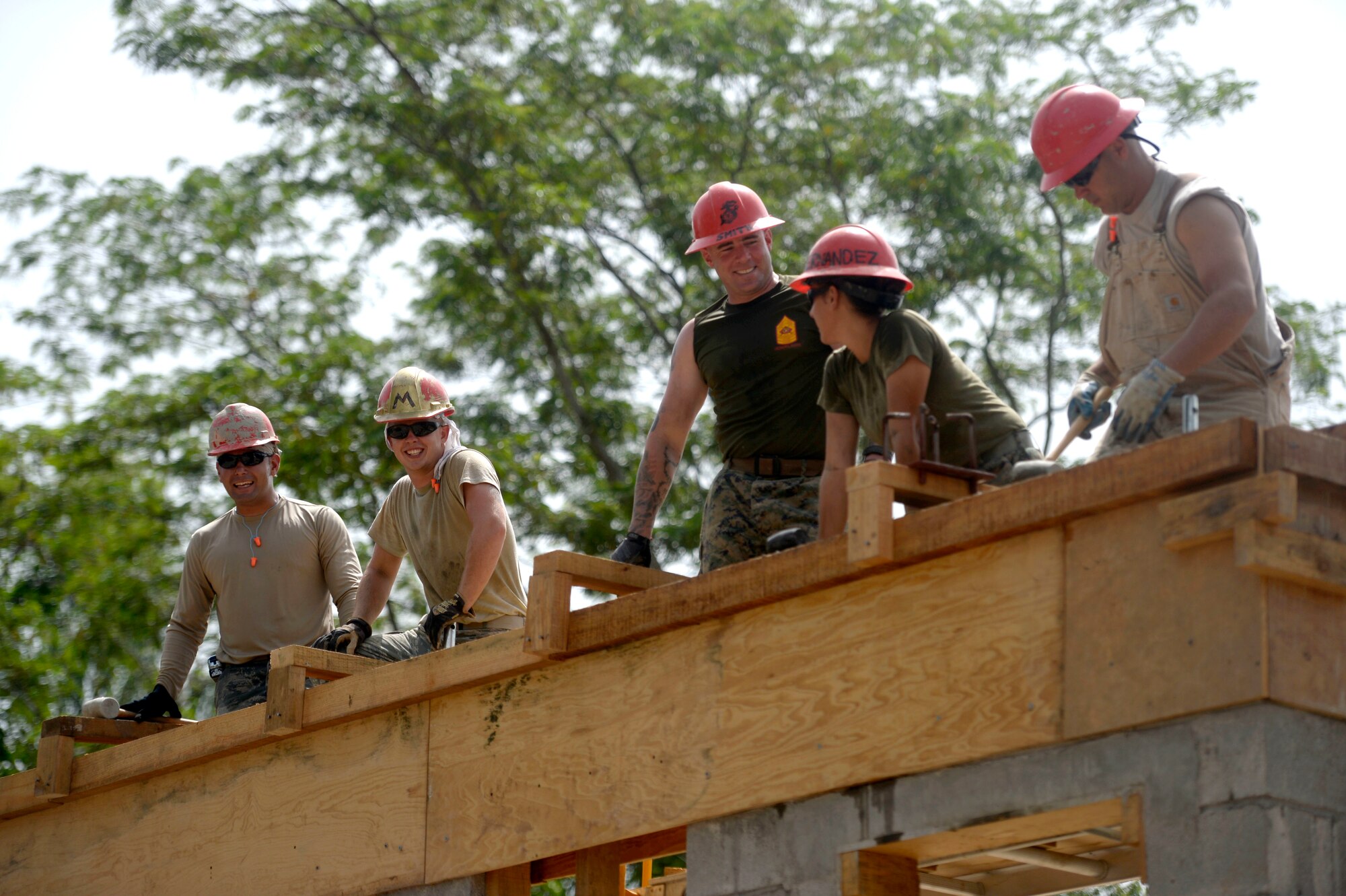 Airmen from the 823rd Expeditionary RED HORSE Squadron, and Marines from the 271st Marine Wing Support Squadron, 2nd Marine Air Wing, work on the bond beam which will be used to hold the roof of the new two-room schoolhouse at the Gabriela Mistral primary school site in the village of Ocotes Alto near Trujillo, Honduras, June 22, 2015. The building is one of multiple projects going on in and around Trujillo and Tocoa as part of NEW HORIZONS Honduras 2015 training exercise. NEW HORIZONS was launched in the 1980s and is an annual joint humanitarian assistance exercise that U.S. Southern Command conducts with a partner nation in Central America, South America or the Caribbean. The exercise improves joint training readiness of U.S. and partner nation civil engineers, medical professionals and support personnel through humanitarian assistance activities. (U.S. Air Force photo by Capt. David J. Murphy/Released)