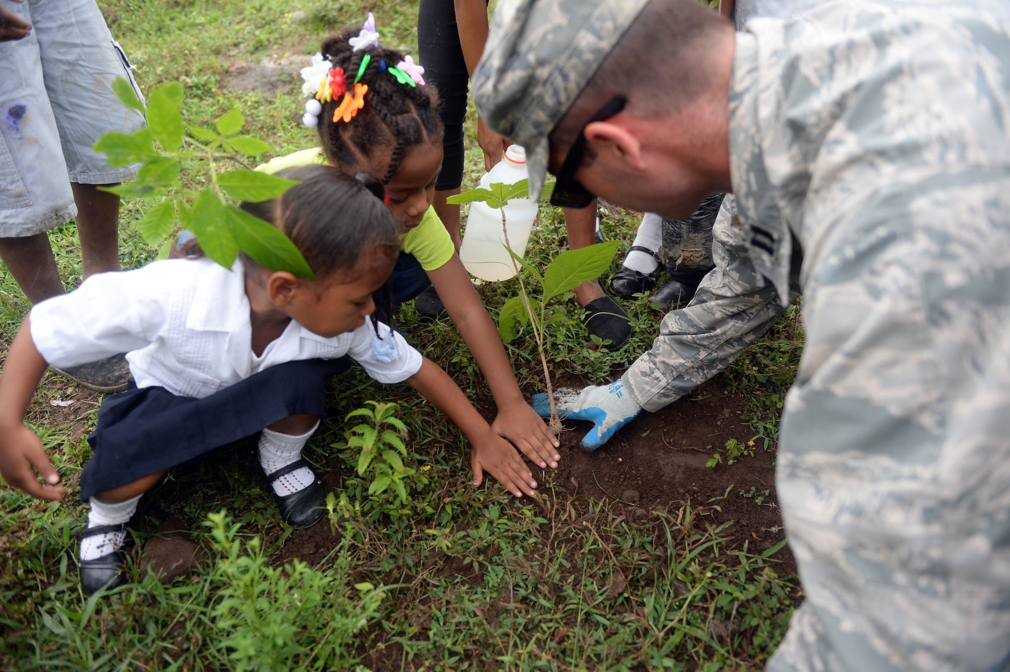 U.S. Air Force Capt. Austin McKinney, 12th Air Force assessments officer in charge, helps students plant trees during the National Tree Day celebration at Rafeal Peneda Ponce School in Trujillo, Honduras, June 19, 2015. McKinney is a member of the NEW HORIZONS Honduras 2015 training exercise which is providing support throughout the Trujillo and Tocoa regions of Honduras by building a new two-classroom schoolhouse in Ocotes Alto, drilling a well in Honduras Aguan, and proving general medical support. NEW HORIZONS was launched in the 1980s and is an annual joint humanitarian assistance exercise that U.S. Southern Command conducts with a partner nation in Central America, South America or the Caribbean. The exercise improves joint training readiness of U.S. and partner nation civil engineers, medical professionals and support personnel through humanitarian assistance activities. (U.S. Air Force photo by Capt. David J. Murphy/Released)