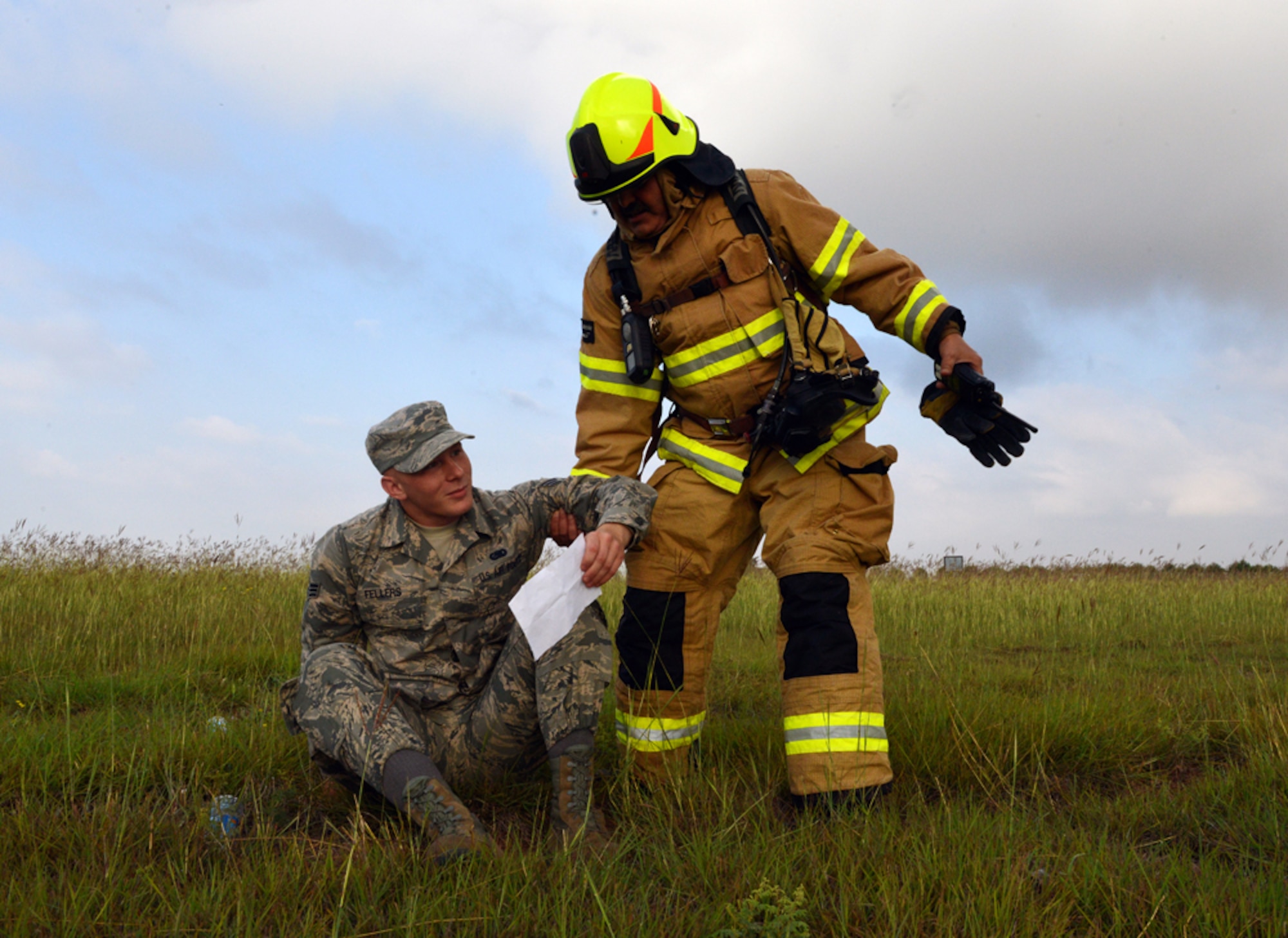 A fire emergency services firefighter from the 39th Civil Engineer Squadron helps up Senior Airman Lloyd Fellers, 39th Logistics Readiness Squadron fuels training monitor, during a mass accident response exercise June 25, 2015, at Incirlik Air Base, Turkey. The exercise tested the base’s ability to quickly respond to a major incident involving mass casualties to include accurate and timely accountability. (U.S. Air Force photo by Senior Airman Michael Battles/Released)