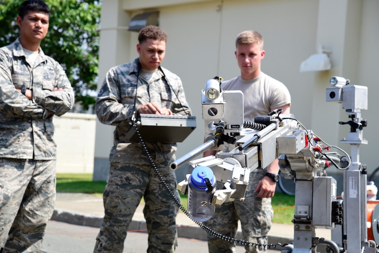 U.S. Air Force Staff Sgt. Brandon Elmore, 35th Aircraft Maintenance Squadron lead load crew member, uses an F-6A Robot to pick up a water bottle during a job swap at Misawa Air Base, Japan, June 23, 2015. This robot is a tool used by explosive ordnance disposal Airmen for remotely interrogating suspect packages, picking up munitions, and other operations. (U.S. Air Force photo by Airman 1st Class Jordyn Fetter/Released)