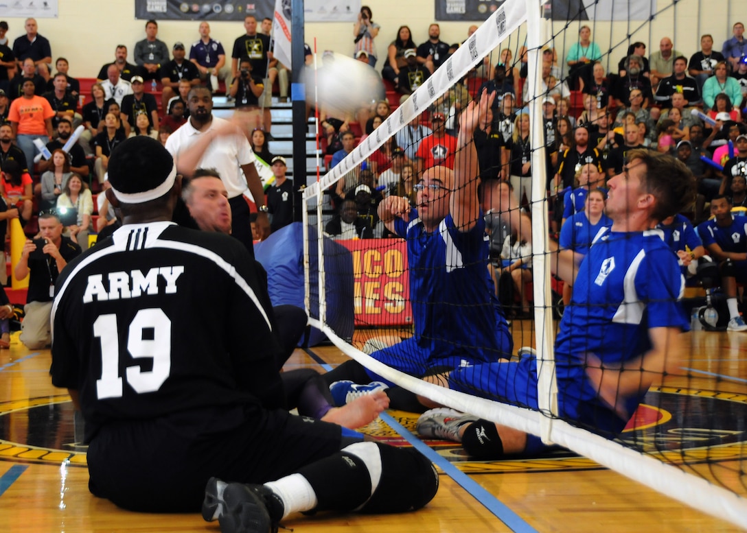 Army Sgt. Patrick Timmins volleys the ball as the Air Force Tech. Sgt. Jason Caswell and Staff Sgt. Zachary Burnash defend during the gold-medal volleyball match during the 2015 Department of Defense Warrior Games at Marine Corps Base Quantico, Va., June 28, 2015. The Army team earned the gold medal in a three-game match. DoD photo by Shannon Collins