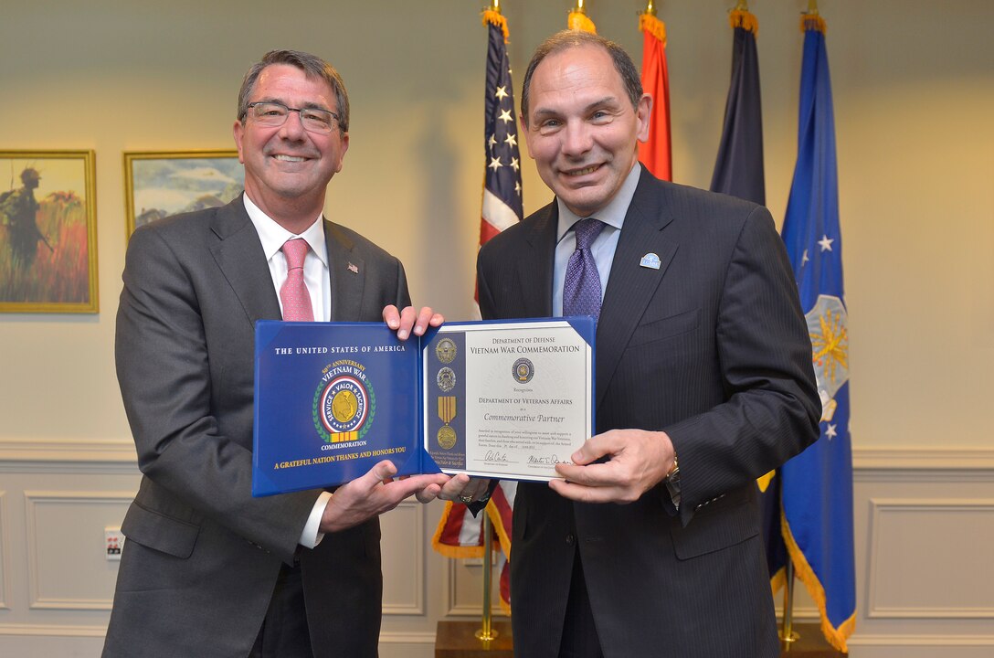 Defense Secretary Ash Carter, left, and Veterans Affairs Secretary Robert A. McDonald hold a document acknowledging that the VA is a commemorative partner in efforts to mark the 50th anniversary of the Vietnam War at the Pentagon, June 29, 2015.