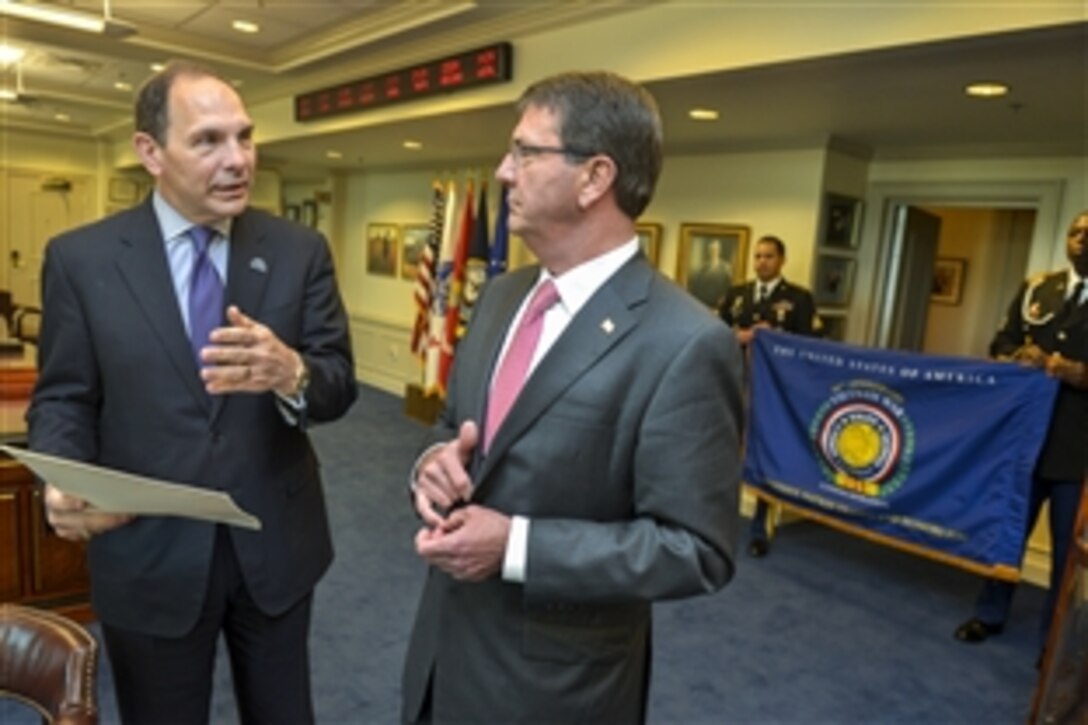Defense Secretary Ash Carter, right, presents Veterans Affairs Secretary Robert A. McDonald with a commemorative flag marking the 50th anniversary of the Vietnam War during an office call at the Pentagon, June 29, 2015.