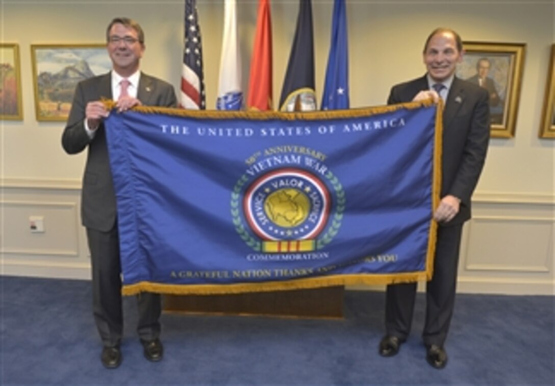 Defense Secretary Ash Carter, left, presents Veterans Affairs Secretary Robert A. McDonald with a commemorative flag marking the 50th anniversary of the Vietnam War during an office call at the Pentagon, June 29, 2015.