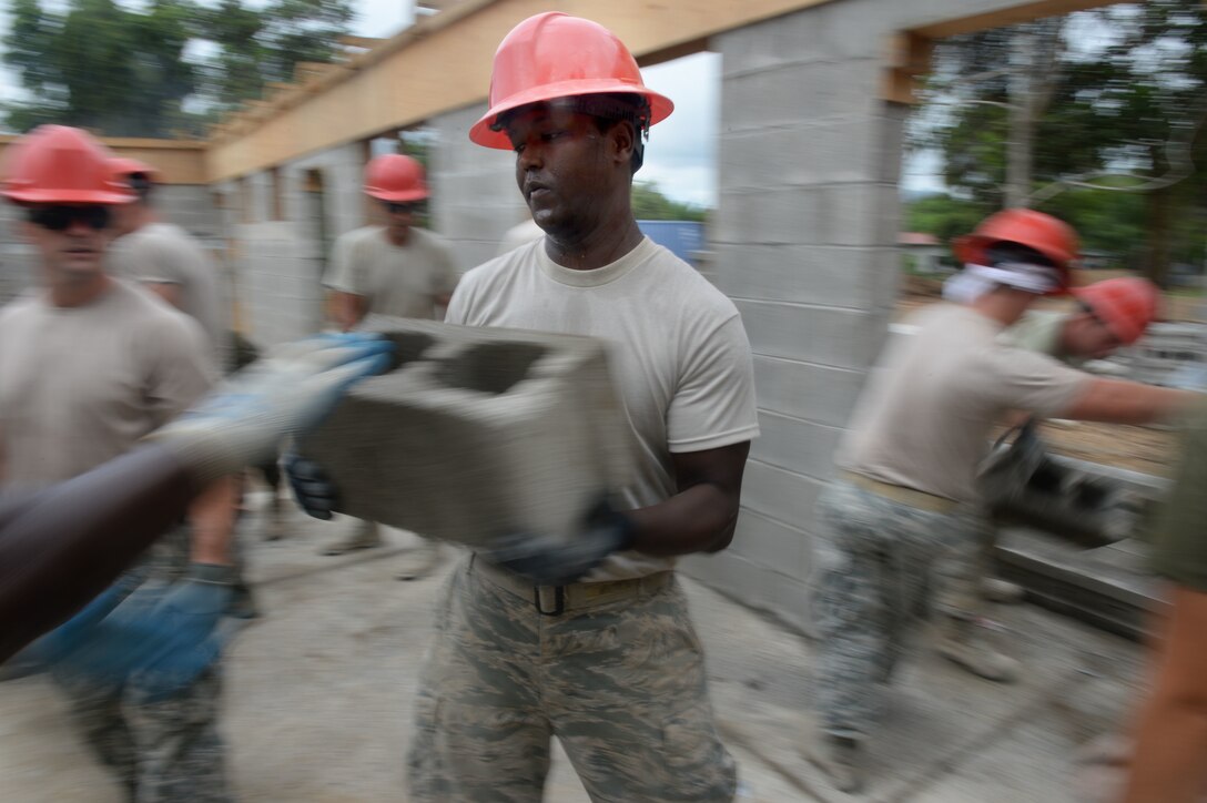 Airmen from the 823rd Expeditionary RED HORSE Squadron, and Marines from the 271st Marine Wing Support Squadron, 2nd Marine Air Wing, move bricks to the interior of the new two-room schoolhouse which will be used to create the interior walls of the building at the Gabriela Mistral school construction site in the village of Ocotes Alto near Trujillo, Honduras, June 24, 2015. The building is one of multiple projects going on in and around Trujillo and Tocoa as part of NEW HORIZONS Honduras 2015 training exercise. NEW HORIZONS was launched in the 1980s and is an annual joint humanitarian assistance exercise that U.S. Southern Command conducts with a partner nation in Central America, South America or the Caribbean. The exercise improves joint training readiness of U.S. and partner nation civil engineers, medical professionals and support personnel through humanitarian assistance activities. (U.S. Air Force photo by Capt. David J. Murphy/Released)