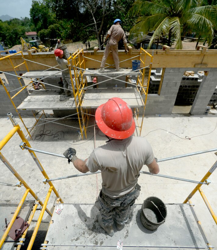 Airmen from the 823rd Expeditionary RED HORSE Squadron, out of Hurlburt Field, Fla., and Marines from the 271st Marine Wing Support Squadron, 2nd Marine Air Wing, based out of Marine Corps Air Station Cherry Point, N.C., work on the bond beam which will be used to hold the roof of the new two-room schoolhouse at the Gabriela Mistral primary school site in the village of Ocotes Alto near Trujillo, Honduras, June 22, 2015. The building is one of multiple projects going on in and around Trujillo and Tocoa as part of NEW HORIZONS Honduras 2015 training exercise. The school project is one part of the NEW HORIZONS Honduras 2015, an annual humanitarian and training exercise put on by U.S. Southern Command. NEW HORIZONS was launched in the 1980s and is an annual joint humanitarian assistance exercise that U.S. Southern Command conducts with a partner nation in Central America, South America or the Caribbean. The exercise improves joint training readiness of U.S. and partner nation civil engineers, medical professionals and support personnel through humanitarian assistance activities. (U.S. Air Force photo by Capt. David J. Murphy/Released)