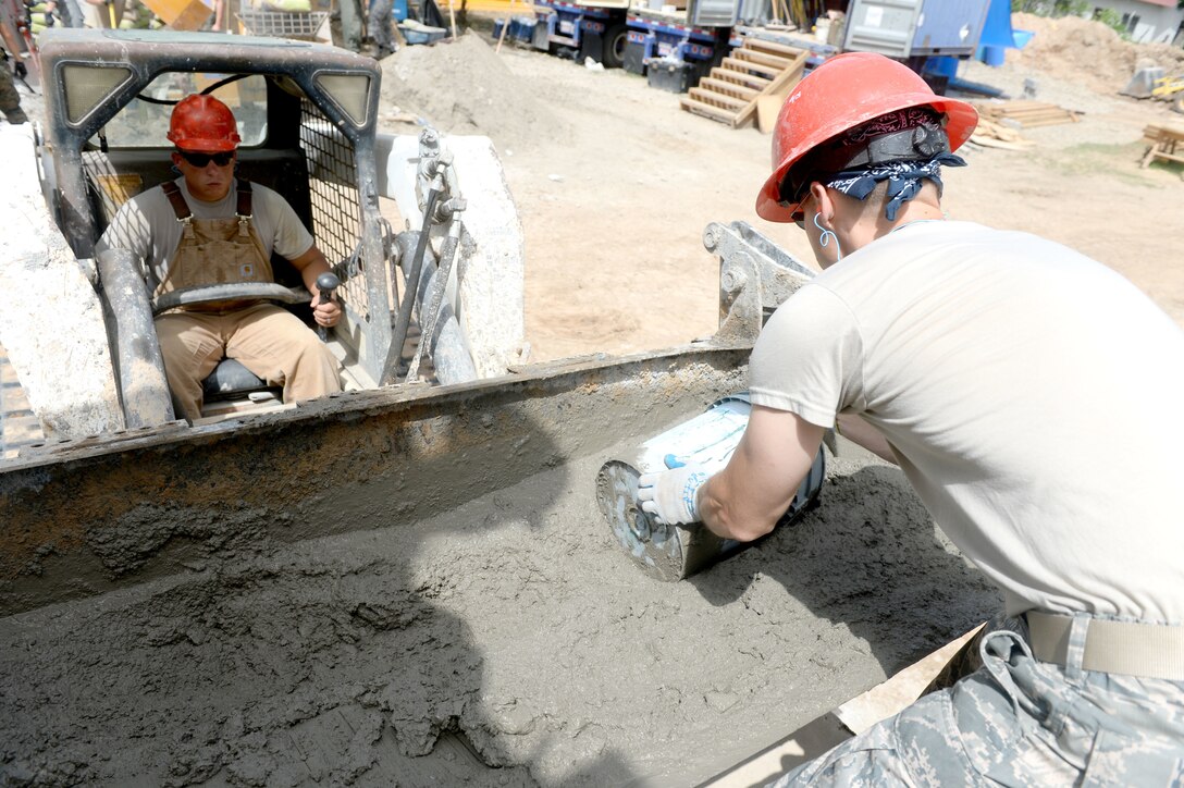 U.S. Air Force Staff Sgt. Michael Zemke, 823rd Expeditionary RED HORSE Squadron, pavements and heavy equipment operator, moves cement via a Bobcat T250 so U.S. Air Force Maj. William Toronto, NEW HORIZONS Honduras 2015 staff judge advocate, and others can help create the bond beam for the new two-room schoolhouse at the Gabriela Mistral primary school in Ocotes Alto, Honduras, June 22, 2015. The school project is one part of the NEW HORIZONS Honduras 2015, an annual humanitarian and training exercise put on by U.S. Southern Command. NEW HORIZONS was launched in the 1980s and is an annual joint humanitarian assistance exercise that U.S. Southern Command conducts with a partner nation in Central America, South America or the Caribbean. The exercise improves joint training readiness of U.S. and partner nation civil engineers, medical professionals and support personnel through humanitarian assistance activities. (U.S. Air Force photo by Capt. David J. Murphy/Released)