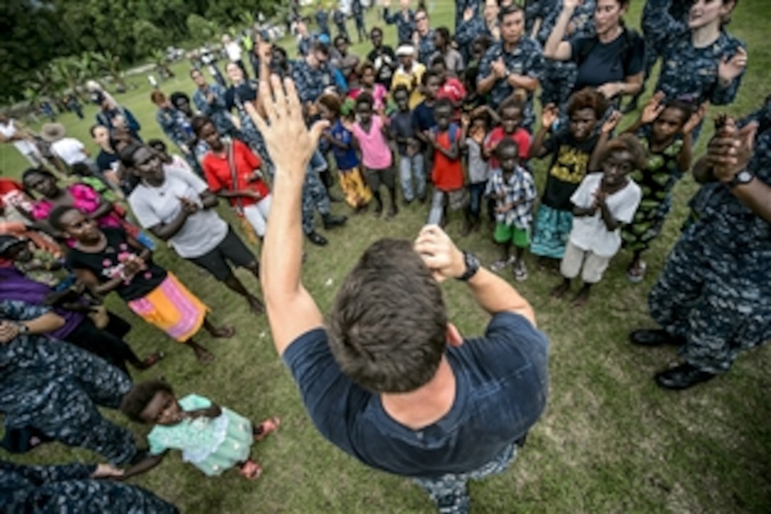 U.S. Navy Petty Officer Class Steve Lamonica interacts with a crowd while performing during Pacific Partnership 2015 in Arawa, Papua New Guinea, June 28, 2015. Lamonica is a musician attached to the hospital ship USNS Mercy.