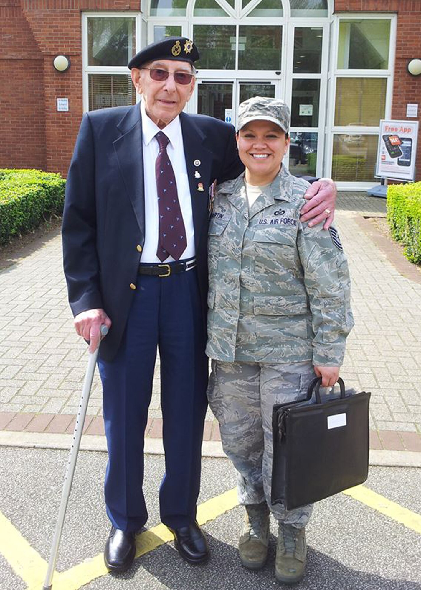 U.S. Air Force Tech. Sgt. Rebeca Martin, right, 352nd Special Operations Support Squadron Aircraft Flight Equipment NCO in charge from San Francisco, poses for a photo with Harold Burgh, a British World War II veteran, at the Holocaust remembrance luncheon April 28, 2014, on RAF Mildenhall, England. Martin was committee lead for the Holocaust Remembrance luncheon where Burgh, a former warrant officer in the Royal Electrical and Mechanical Engineers, was guest speaker. Burgh passed away in 2014. (Courtesy photo/Released)