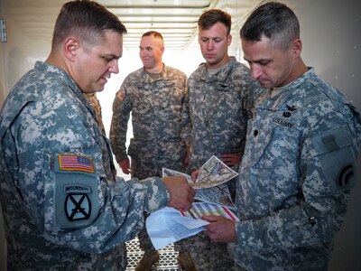 New York Army National Guard Lt. Col. Kevin Ferreira, right, the operations officer for the 42nd Combat Aviation Brigade discusses a simulated helicopter mission behind enemy lines with his counterparts from the 10th Combat Aviation Brigade on June 17, 2015 at Fort Drum, New York, as part of a Multi-echelon Integrated Brigade Training exercise conducted during annual training. 