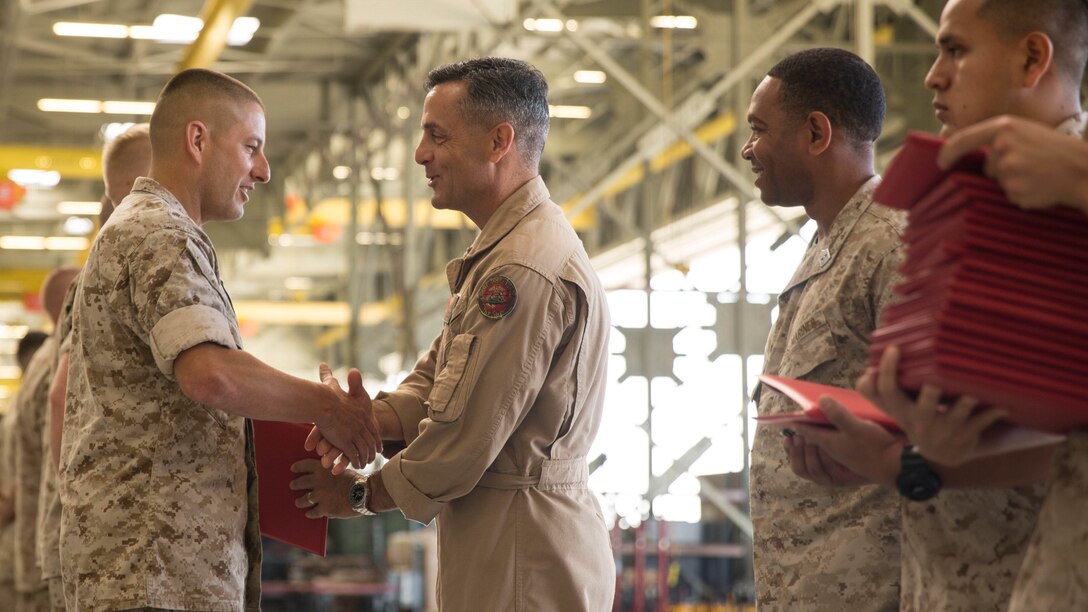 Maj. Gen. Michael Rocco, commanding general of 3rd Marine Aircraft Wing, awards Master Gunnery Sgt. Kevin Anderson, a maintenance chief with Marine Tiltrotor Squadron 166, the Navy and Marine Corps Commendation Medal inside Hangar 6 aboard Marine Corps Air Station Miramar, Calif., June 25, 2015. A team of twenty-four Marines from VMM-166, VMM-268 and VMM-364 received awards for playing a role in returning a grounded MV-22 Osprey to operational flight status.