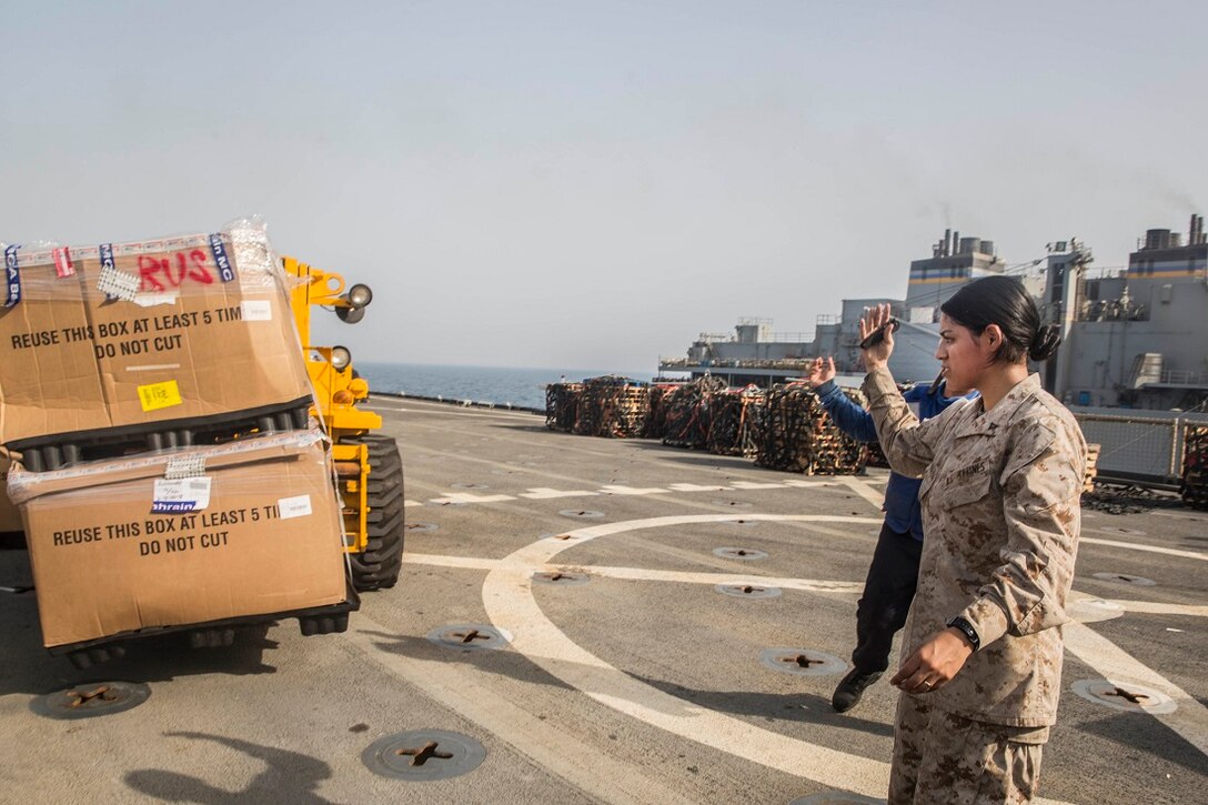 U.S. Marine Lance Cpl. Jasmine Castaneda guides a fork lift operator during a replenishment at sea aboard the Whidbey Island-class dock landing ship USS Rushmore (LSD 47). Castaneda is a supply warehouse clerk with Combat Logistics Battalion 15, 15th Marine Expeditionary Unit.  Marines and sailors with the 15th MEU and Essex Amphibious Ready Group worked together to offload food, maintenance parts, and letters from home. The 15th MEU is embarked on the Essex ARG and deployed to maintain regional security in the U.S. 5th Fleet area of operations. (U.S. Marine Corps photo by Sgt. Emmanuel Ramos/Released)