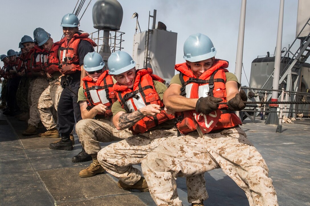 U.S. Marines with the 15th Marine Expeditionary Unit tighten the slack on a rope during a replenishment at sea aboard the Whidbey Island-class dock landing ship USS Rushmore (LSD 47). Marines and sailors with the 15th Marine Expeditionary Unit, and Essex Amphibious Ready Group worked together to offload food, maintenance parts, and letters from home. The 15th MEU is embarked on the Essex ARG and deployed to maintain regional security in the U.S. 5th Fleet area of operations. (U.S. Marine Corps photo by Sgt. Emmanuel Ramos/Released)